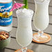 Two glasses of tropical drink with coconut and pineapple garnish.