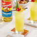 Two glasses of yellow drinks garnished with pineapple and a cherry.