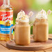 Two glass mugs of brown coffee with whipped cream and honey on top.