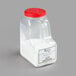 A clear plastic container of white powder with a white label and a red lid.