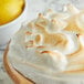 A lemon meringue pie with a lemon wedge on a table.