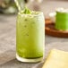 A glass of Dona Kyoto Ceremonial Matcha green drink with a straw.