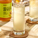 A glass of liquid with honey and ice on a table with a bottle of Assi Korean Citron Tea with Honey syrup.
