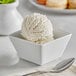 A white bowl with a scoop of Oringer coconut ice cream on a table with a spoon.