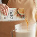 A person pouring Tazo Chai Tea Latte concentrate into a pitcher.