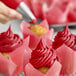 A close-up of a Chefmaster Super Red Liqua-Gel pink frosted cupcake.