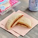 A Smucker's Uncrustables peanut butter and raspberry spread sandwich on a napkin.