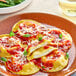 A plate of Seviroli Stracciatella Burrata Round Ravioli with sauce and cheese.