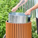 A round outdoor trash can with a wood composite exterior and a removable steel inner liner.