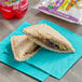 An Individually wrapped SunWise SunButter and Grape sandwich on a blue napkin.