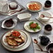 A table with white plates and bowls of food, including Acopa Keystone mini rarebit dishes.