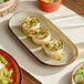 An Acopa Keystone granite gray porcelain oblong coupe platter with food on a table.