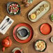 An orange Acopa Keystone shirred egg casserole dish on a table with food.