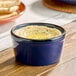 A blue porcelain ramekin filled with a creamy dip, likely hummus.