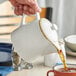 A hand pouring tea into an Acopa vanilla bean porcelain teapot.