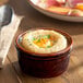 An Acopa Keystone chestnut porcelain ramekin filled with food on a table.