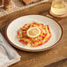 A plate of ravioli with a lemon wedge on it.