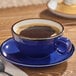 A blue porcelain cup filled with coffee, placed on a matching saucer.