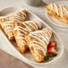 A white plate of pastries made with Pennant French Puff Pastry Dough and strawberries with white frosting.