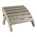 A Lancaster Table & Seating gray high impact polystyrene Adirondack footrest on a wooden table on a patio.