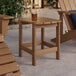A Lancaster Table & Seating brown high impact polystyrene Adirondack side table with a drink on it.