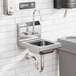 A close-up of a stainless steel wall-mounted hand sink with a T&S faucet.