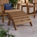 A brown Lancaster Table & Seating Adirondack footrest on a patio.