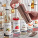 A hand pouring Capora Raspberry Flavoring Syrup into a metal cup.