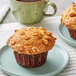 A David's Cookies banana nut muffin on a plate with nuts and a cup of coffee.
