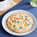 A David's Cookies Decadent Celebration cookie with multicolored candy on a plate.