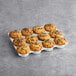 A tray of David's Cookies chocolate chip muffins on a table in a bakery display.