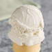 A scoop of G.S. Gelato Tahitian Vanilla Bean Gelato in a white ice cream cone.