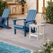 Two blue Lancaster Table & Seating Adirondack chairs on a patio next to a pool.