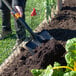 A person using a True Temper square point shovel to dig in the dirt.