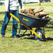 A person pushing a True Temper wheelbarrow full of wood.