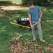 A man using a True Temper steel tine leaf rake to pick up leaves.