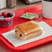 A Brioche Gourmet chocolate croissant wrapped in plastic on a red tray.