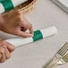 A person's hands wrapping a napkin with a green Choice paper band.