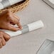 A person's hands using a Choice Silver self-adhering paper napkin band to wrap a stack of paper.