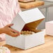 A person opening a white Baker's Lane cake box.