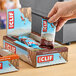 A hand holding a box of Clif Bar Chocolate Brownie energy bars.