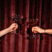 Two women holding Stolzle Kyoto coupe cocktail glasses filled with wine.