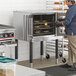 A single deck electric full size convection oven with legs in a commercial kitchen setting.