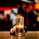 A person in a hat holding a Stolzle Kyoto long drink glass filled with liquid and ice.