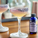 A glass of lavender bitters next to a lavender cocktail.