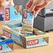 A hand holding a box of Clif Bar White Chocolate Macadamia Nut Energy Bars.
