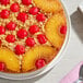 A pineapple upside-down cake topped with maraschino cherries and pineapple rings on a white plate.
