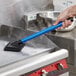 A hand using a blue Scrubble pad holder to clean a stove.