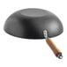 A flat bottom carbon steel wok with a wooden handle, shown upside down.