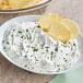 A bowl of white dip with chips.